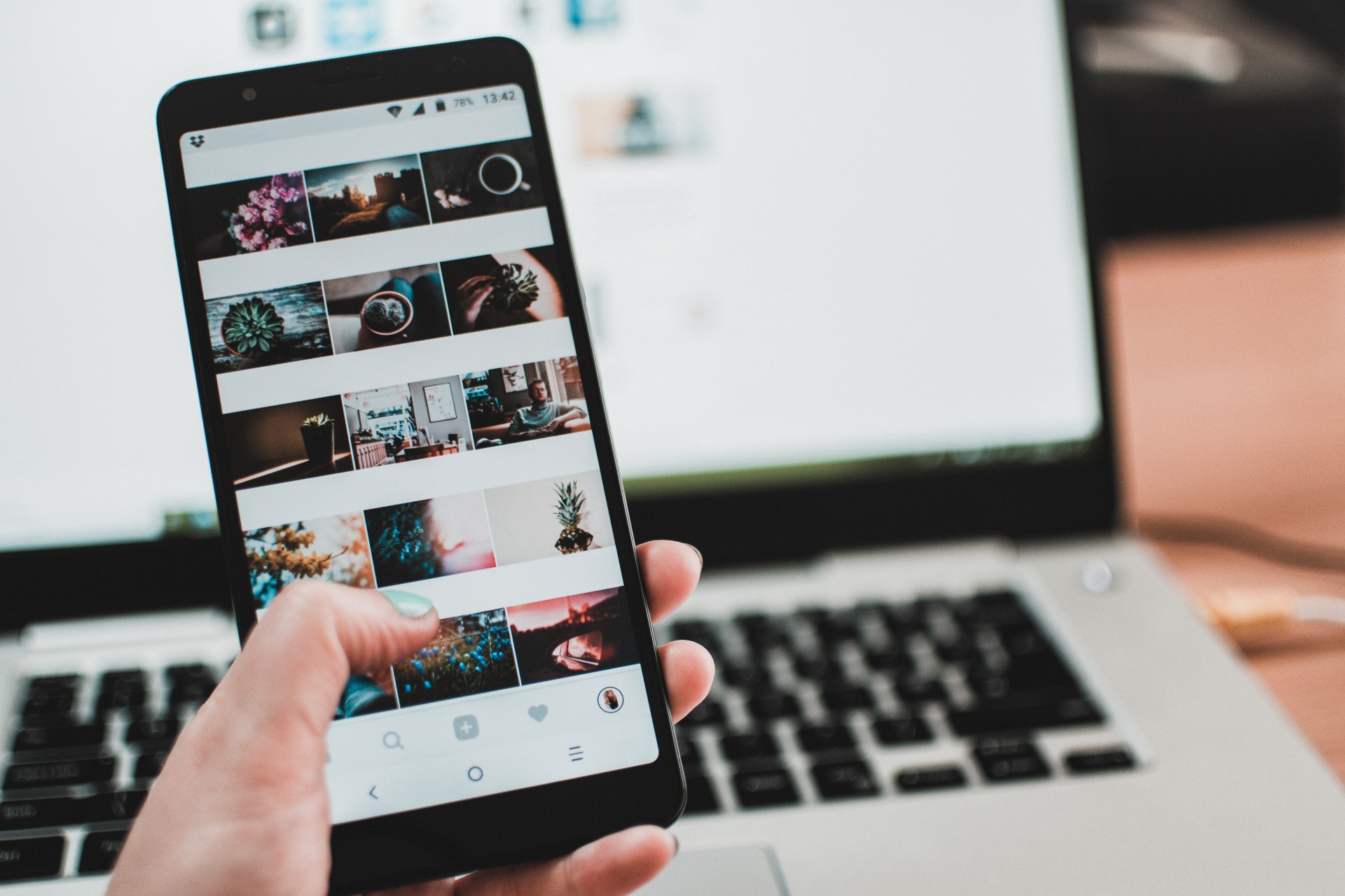 Phone gallery beign scrolled in front of a laptop